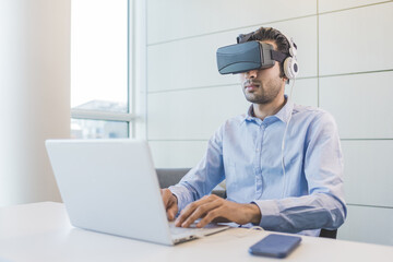 Young indian businessman using 3D viewer and computer