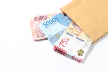 Random Layout Photo Rupiah Paper Money, 10000, 50000, 100000 and 75000 at Brown Envelope at White Background