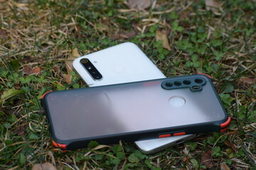 White color smart phone and its cover in green grass