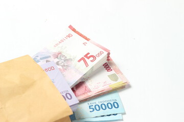 Random Layout Photo Rupiah Paper Money, 10000, 50000, 100000 and 75000 at Brown Envelope at White Background