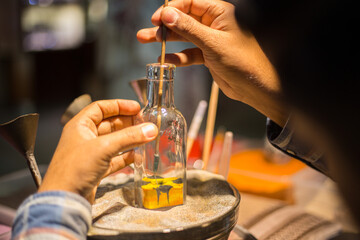 Making camel by sand in the souvenir sand bottle at the Madinat Jumeirah Souk, Dubai, UAE. Craftsman makes souvenirs in a bottle using colored sand