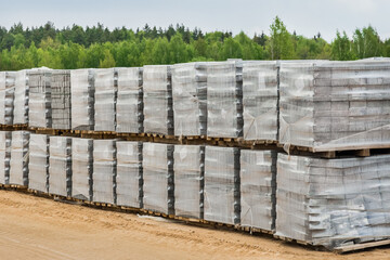 Large pile of packaged paving stone slabs industrial material on pallets at construction site