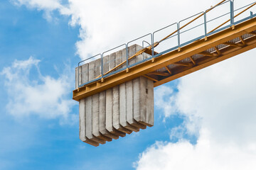 A counterweight of concrete blocks on the tail of a tower crane industrial equipment against a blue...