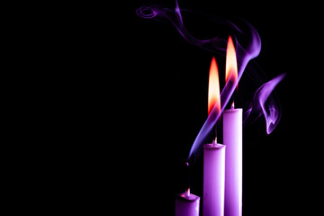 Fototapeta na wymiar Three purple candles were set on fire, two of them had a black background smoke.