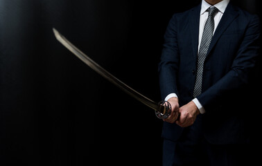 日本刀を構えるスーツ姿の人物