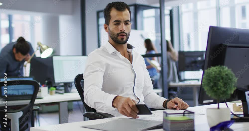 Poster mixed race businessman sitting at desk using computer and smartphone in busy office