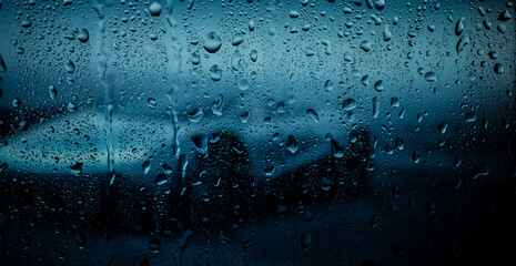 Night city life through windshield. Cars, lights and rain, vintage style photography. City view through a window on a rainy night. Waterdrops on window with road light bokeh.