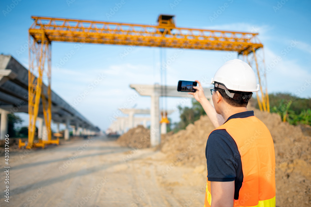 Wall mural smart asian worker man or male civil engineer with protective safety helmet and reflective vest usin