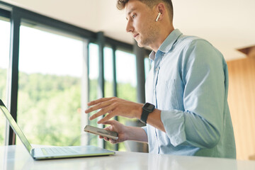 Fototapeta premium Cropped portrait of businessman working from home with laptop and smartphone