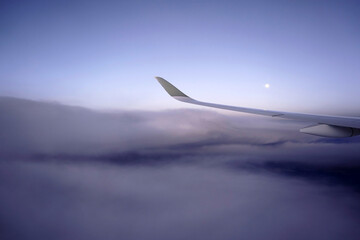 Naklejka na ściany i meble Moon, clouds and the airplane wing, view from the passenger's window.
