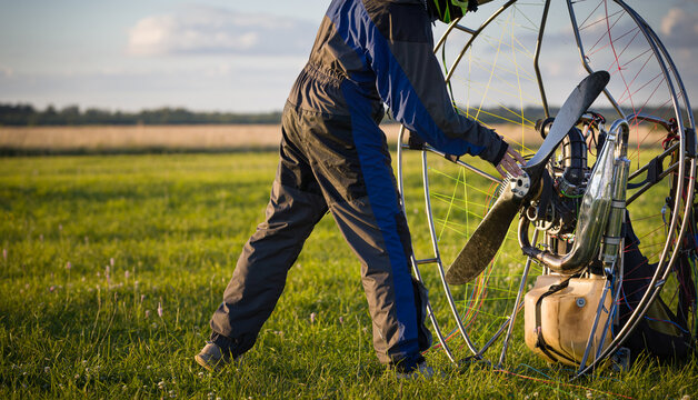The pilot is preparing a paralet with a gasoline engine for flights. The man starts the engine. Paragliding for individual paragliding flights. Wing flight preparation. Extreme sports.