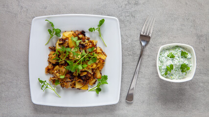 Fried potato dish with fresh microgreens: white mustard greens and watercress with yoghurt dip.