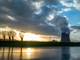 Nuclear power plant against sky by the river at sunset