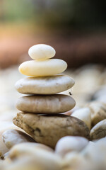 Fototapeta na wymiar Close up still life black and white view of a stack of natural white stones piled on top of each other in balance against a plain background. Neutral, calm and relaxing health spa interior colors. 