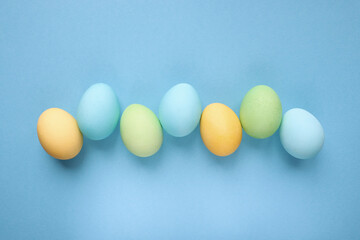 Easter holiday. Painted Easter eggs on a blue background. Pastel colors. Festive background with colorful eggs. Easter egg hunt game. Tradition.