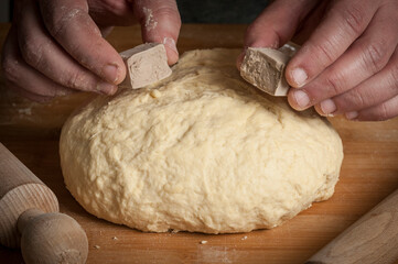 Man breaks a stick of brewer's yeast on top of the bread dough
