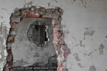 An end-to-end hole in a brick wall inside an old abandoned and ruined industrial building covered with paint in a collapsed building with through holes. High quality photo