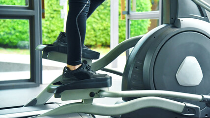 close up of legs of Young sports male during using an elliptic trainer in a fitness center