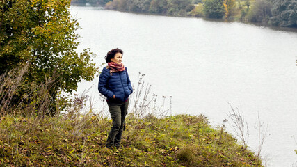 Elderly woman by the river in autumn while walking