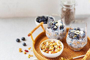 Chia pudding with granola and fresh blueberries in the glasses on a gray concrete background with copy space. Concept of healthy eating, healthy lifestyle, dieting, fitness menu. Selective focus