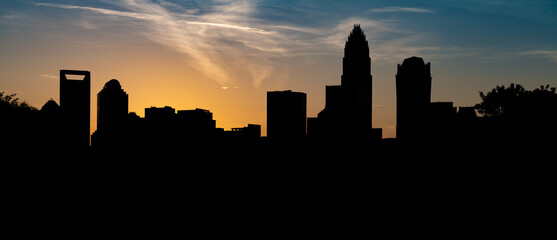 The Charlotte NC skyline silhouetted against the vibrant sky at sunset - obrazy, fototapety, plakaty