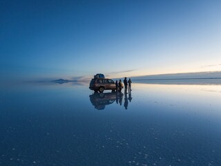 Tourist group with offroad car SUV on Salar de Uyuni salt flat lake in Bolivia andes mountains sunrise mirror reflection © Marc