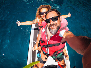 Top view selfie image of joyful young adult couple on a jet sky adventure lifestyle - happy couple...