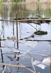 Snack packages, plastic bottles and cigarette butts on the riverbank. Planet pollution concept. Selective focus.