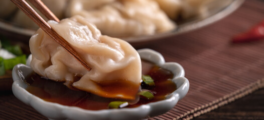 Eating fresh boiled dumpling using chopsticks with soy sauce.