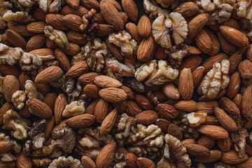 Top view on a flat lay close-up of a bunch of ripe brown nuts of different varieties of walnuts and almonds, healthy and tasty.
