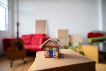 Model of the wooden house on the floor in the new bright sunny house