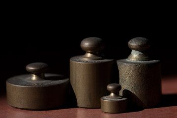 Several metal weights stand in front of a dark background with space for text