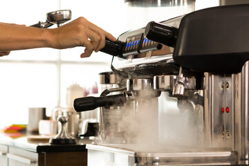 Young Barista preparing and making espresso with coffee machine. Barista preparing portafilter before making cappuccino in a coffee shop.
