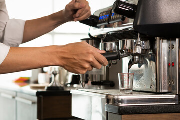 Young Barista preparing and making espresso with coffee machine. Barista preparing portafilter before making cappuccino in a coffee shop.
