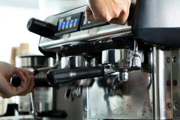 Young Barista preparing and making espresso with coffee machine. Barista preparing portafilter before making cappuccino in a coffee shop. 