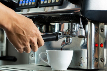 Young Barista preparing and making espresso with coffee machine. Barista preparing portafilter before making cappuccino in a coffee shop. 
