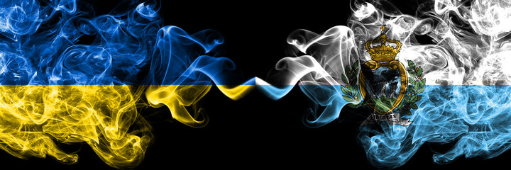 Ukraine, Ukrainian vs San Marino smoky mystic flags placed side by side. Thick colored silky abstract smokes flags.