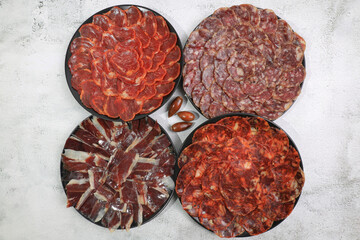 Fototapeta na wymiar Several servings of Iberian sausages: Iberian ham, loin, chorizo and 100% acorn-fed salchichón
