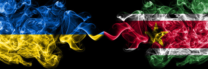 Obraz premium Ukraine, Ukrainian vs Suriname smoky mystic flags placed side by side. Thick colored silky abstract smokes flags.