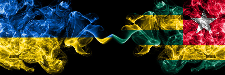 Ukraine, Ukrainian vs Togo smoky mystic flags placed side by side. Thick colored silky abstract smokes flags.