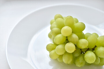 A bunch of green grapes on a white plate