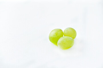 Three grapes close up on a white background