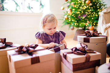 Fototapeta na wymiar Little blonde girl surrounded by Christmas gifts.