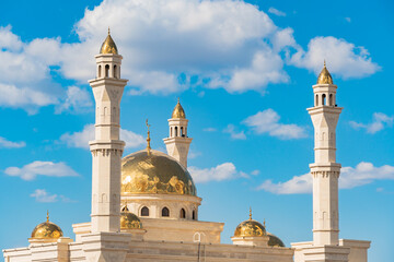 A Muslim Islamic mosque with golden minarets and a crescent moon against the sky.A religious temple for praying and worshipping the God of Muslims in Islamic culture and belief in Allah.