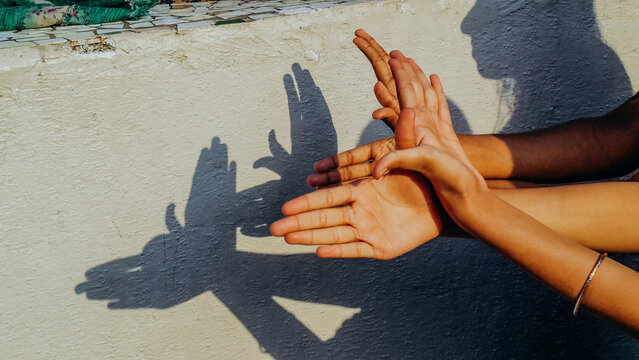 Pair of hands creating shadow puppet in sunshine