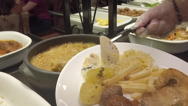 Pouring a sticky goey meal on the dish during the lunch at a buffet restaurant in which you can eat all you can at all meals on a five star hotel