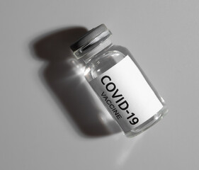 COVID-19 VACCINE ampoule on a gray background.