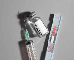 Bottle and syringe with vaccine injection from covid-19 virus on a gray background.