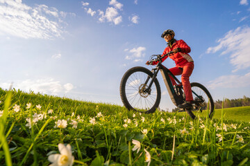 pretty mid age woman riding her electric mountain bike in early springtime in the Allgau mountains...