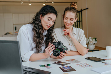 Two young women selecting photos on the camera indoor